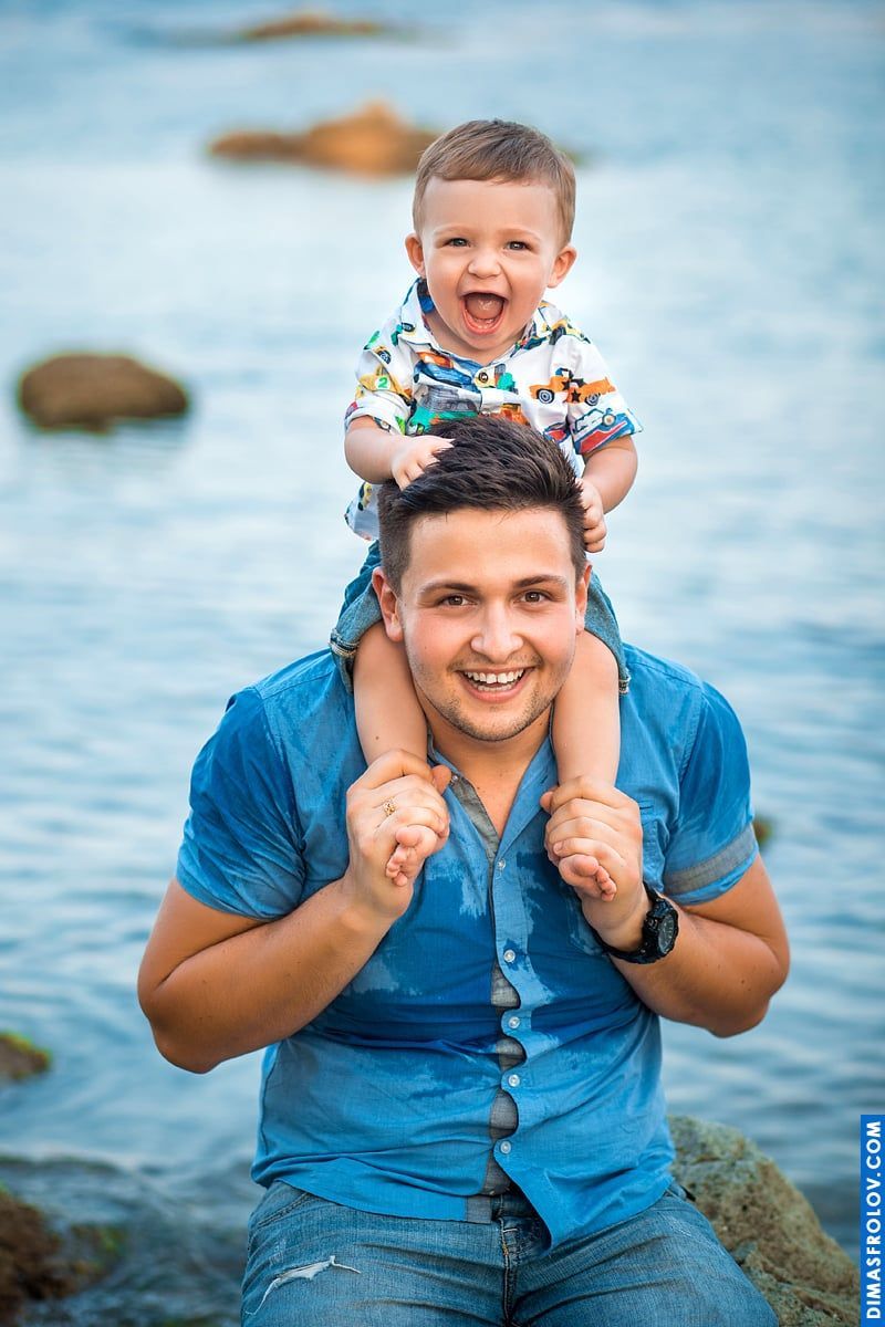 Retrato de pai e filho — ambos sorrindo com alegria à beira-mar