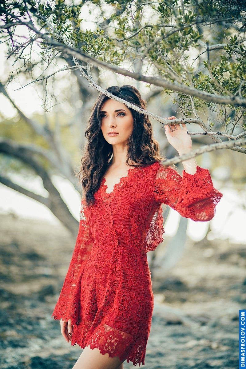 Stylish portrait of a woman in red lace dress among tree branches