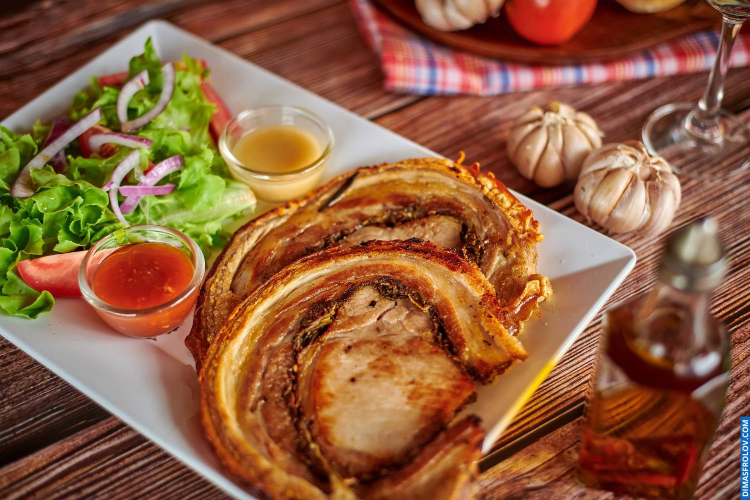 Naturally lit, life-style food shot of sliced porchetta served with salad and sauce on a plate, perfect for bloggers and establishments focusing on real food presentation