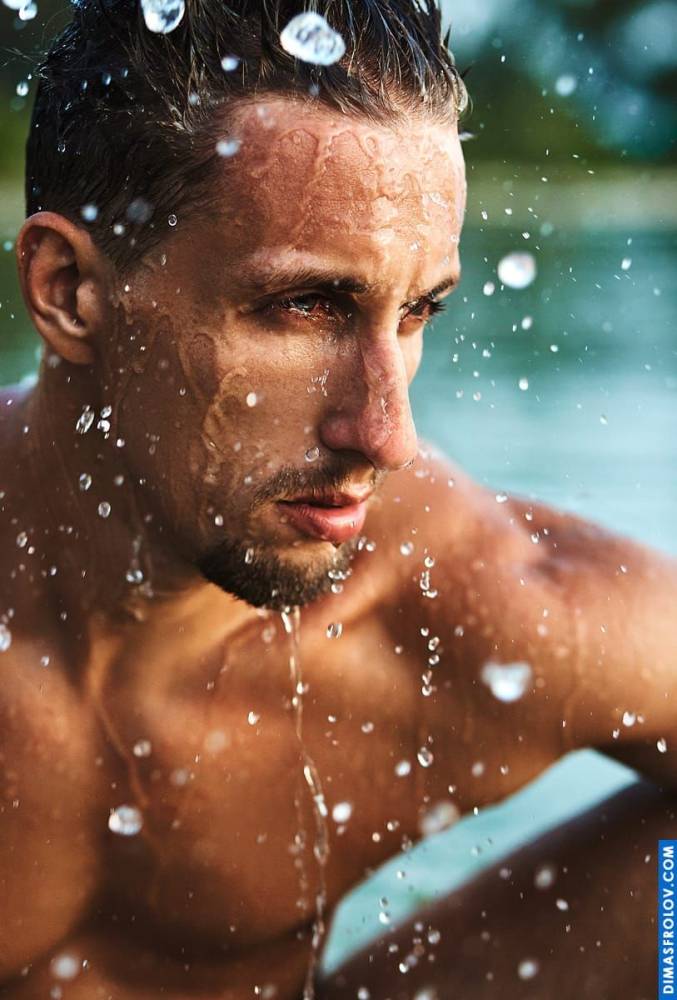 A refreshing water photo shoot: a wet man poses by the shore during a revitalizing photo session