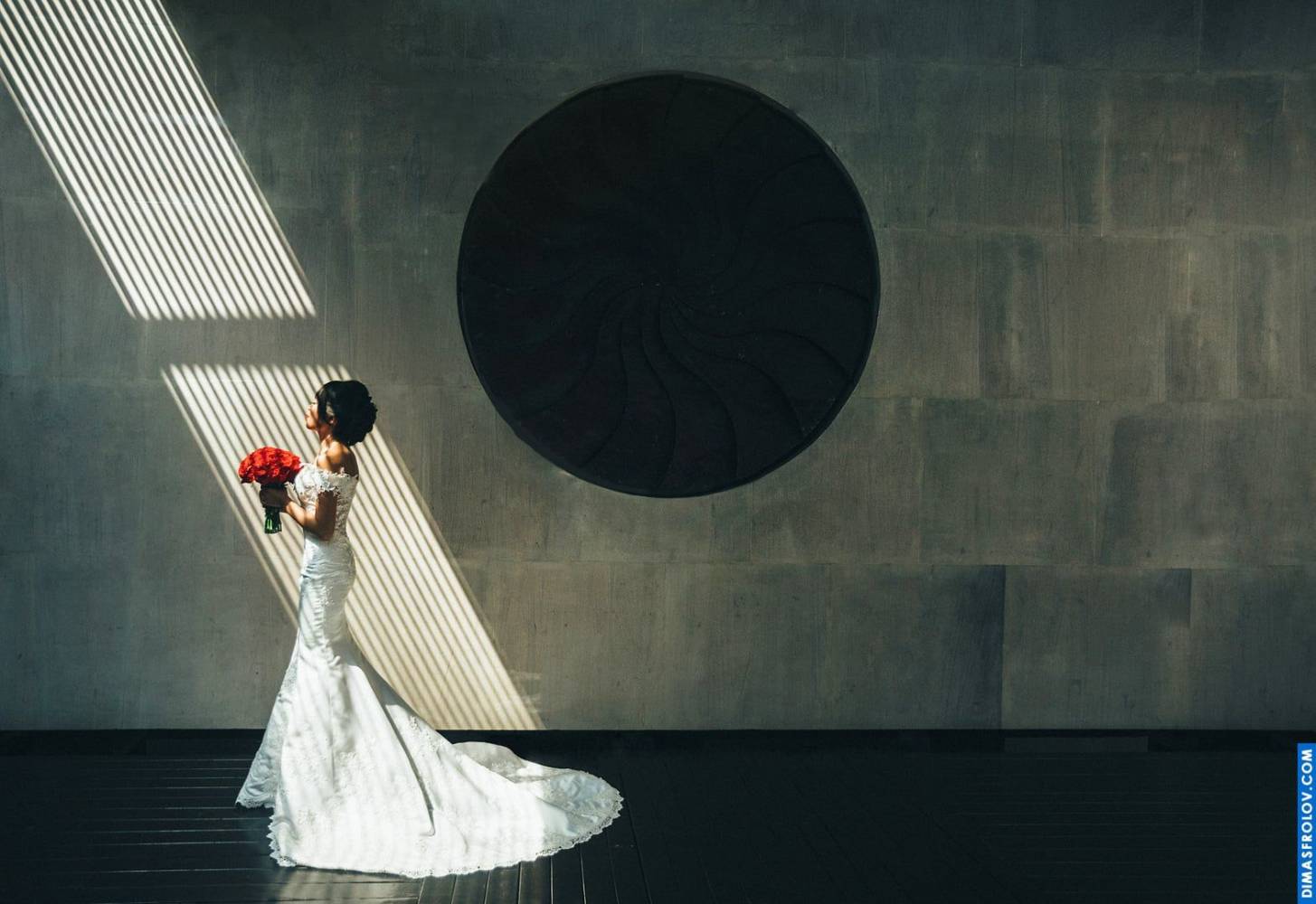 Bride standing in modern interior with dramatic light and shadow