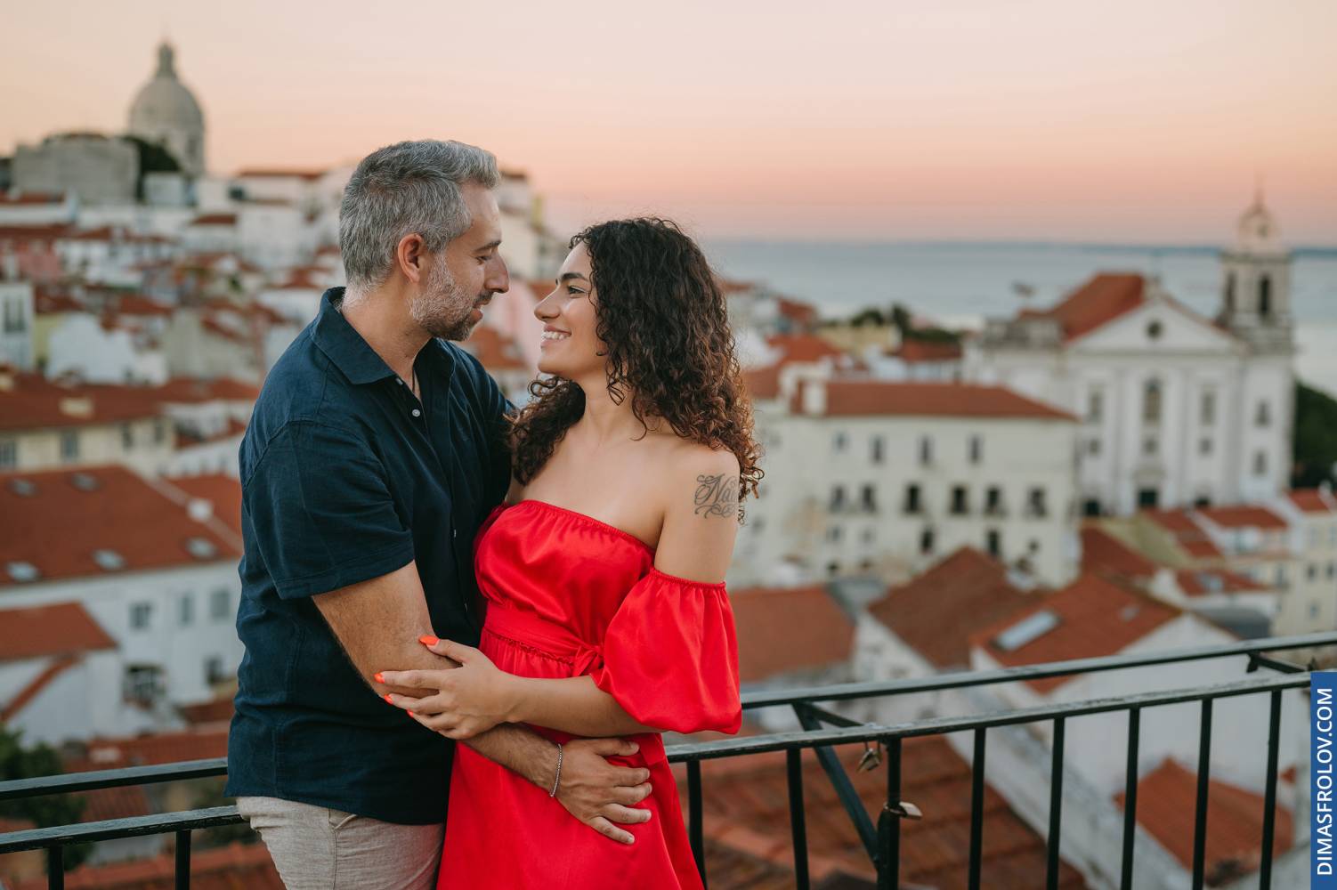 Couple embracing on rooftop terrace at sunset in Lisbon