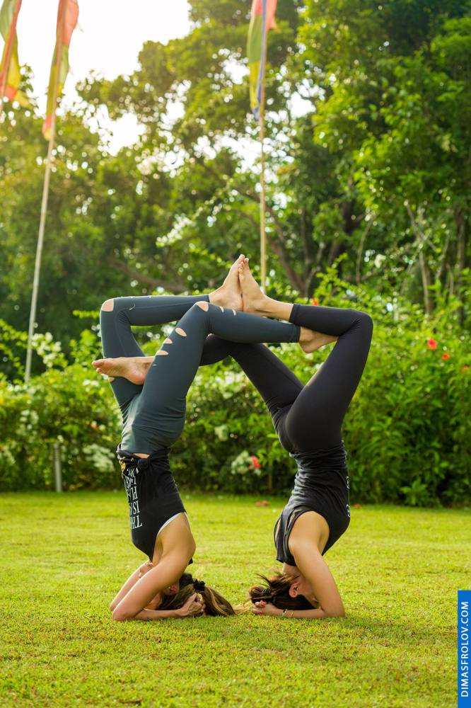 Harmonious acroyoga duo: two women in a balanced headstand pose outdoors
