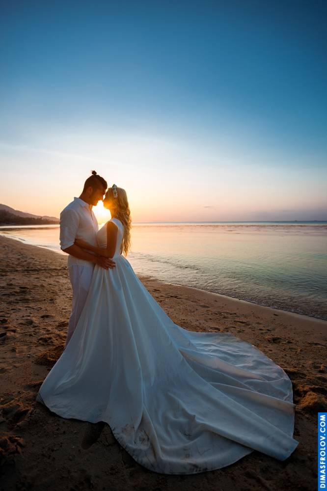 Bride and groom embracing on the shore in golden sunset light
