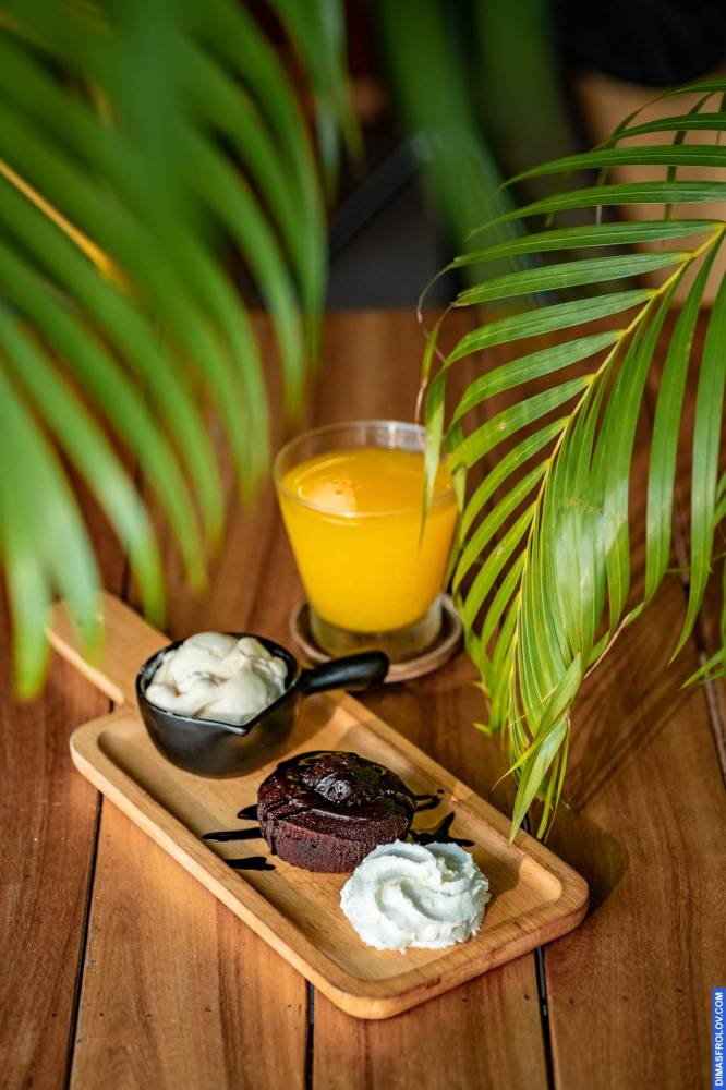 Naturally lit, life-style shot of a wooden platter with dips and orange juice, styled with tropical leaves, perfect for cafes and bloggers showcasing fresh and vibrant offerings
