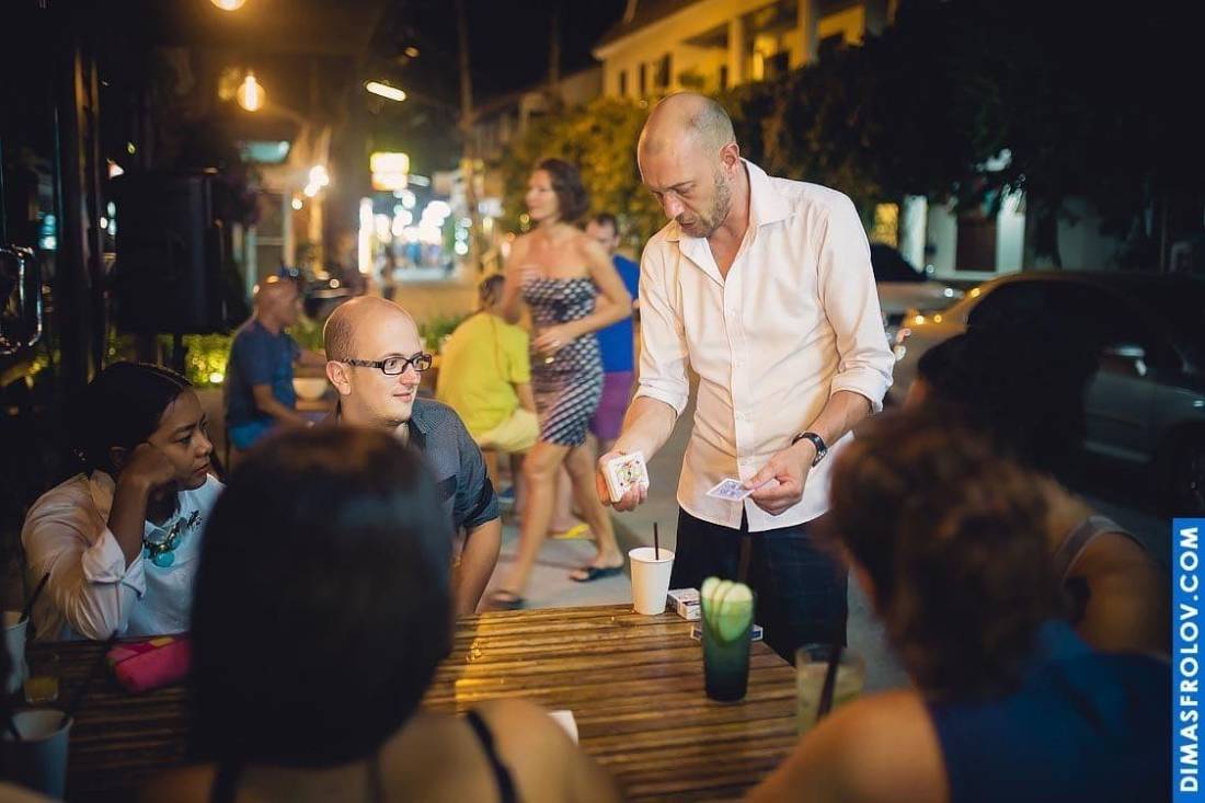 Magician performing tricks at evening party — guests watching with curiosity