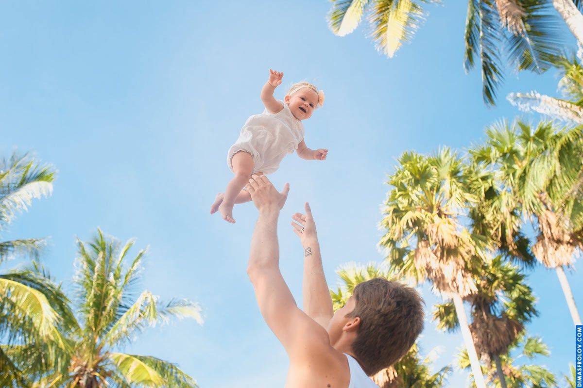 Joyful baby photo session — candid moment of flying baby with tropical sky