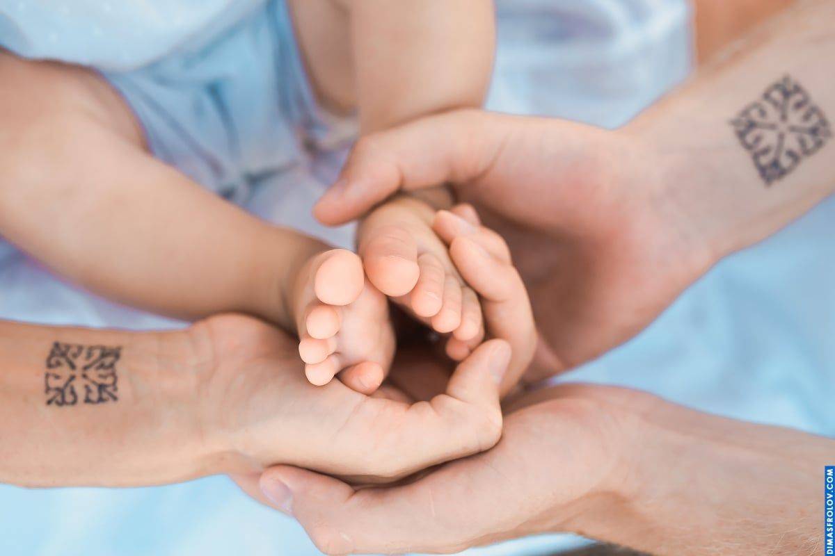 Symbolic family portrait — photo of three generations holding baby-s hand in a meaningful shot