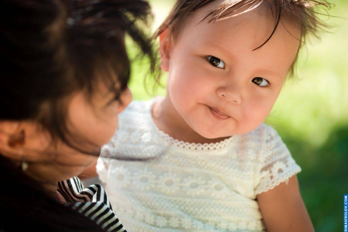 Sweet baby portrait — close-up look with soft smile in mom-s arms