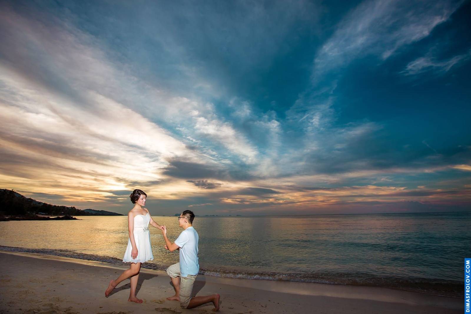 Engagement beach walk photo with dramatic sunset sky