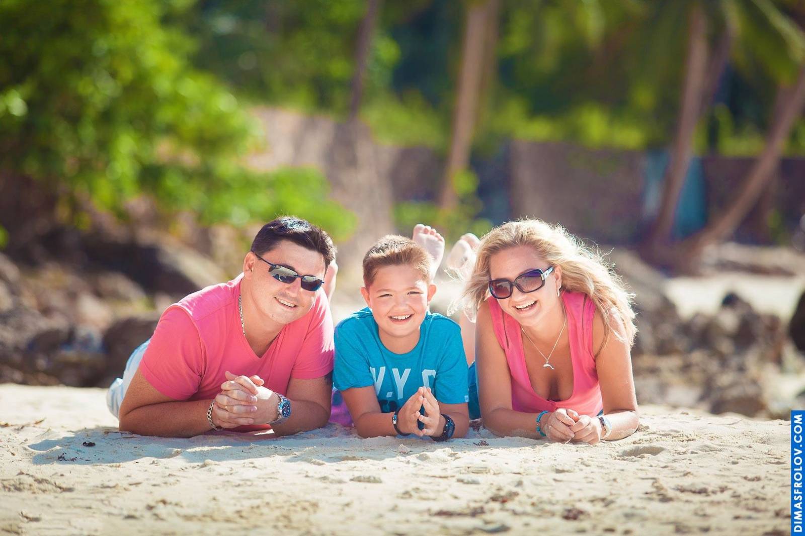 Fun beach portrait — parents with son lying on the sand, smiling together