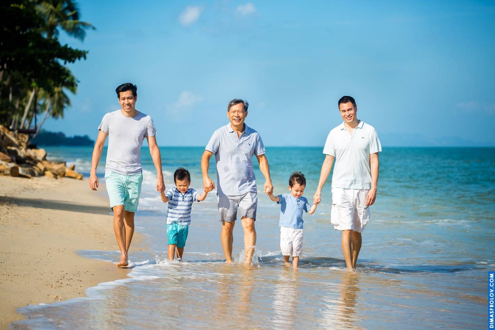 Three generations family photo shoot on the beach — two dads, grandpa and boys in a relaxed portrait