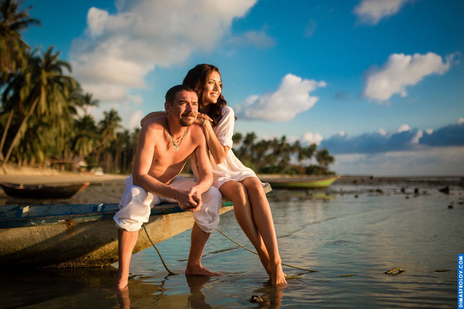 Peaceful couple moment at sunset with a boat in the background and calm shoreline
