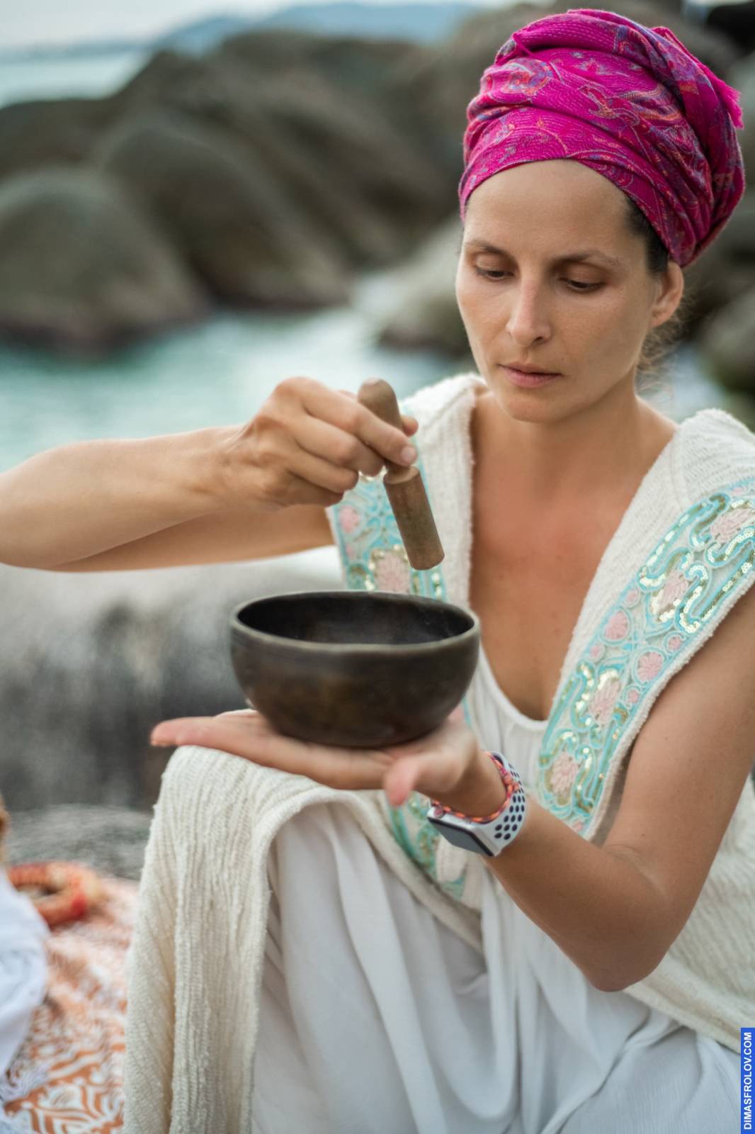 Focused woman playing singing bowl during seaside sound healing ritual