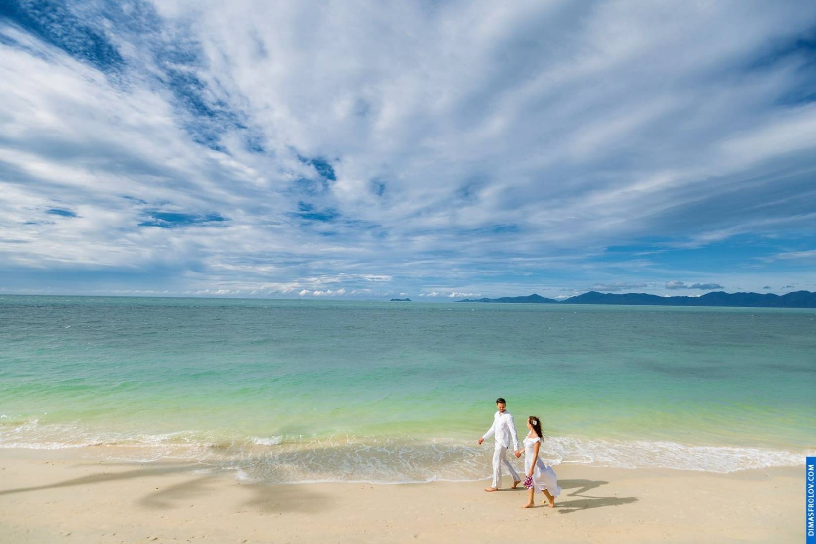 Scenic wide-angle couple photo with clear skies and turquoise water