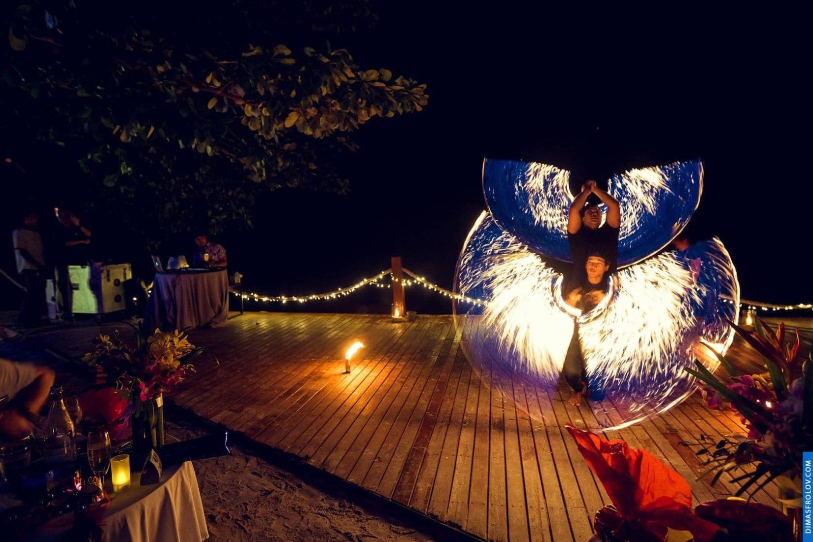 Spectacular fire show performance at night beach party with glowing wings