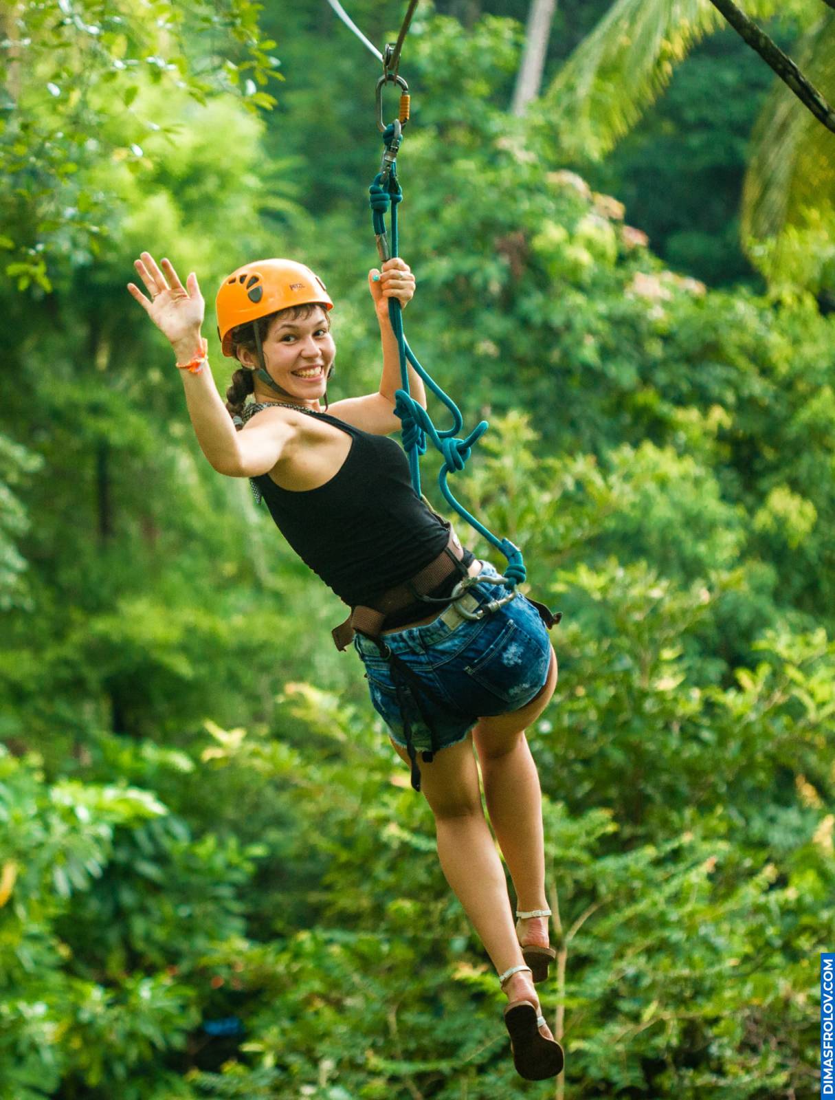 Woman ziplining through tropical jungle with big smile and helmet