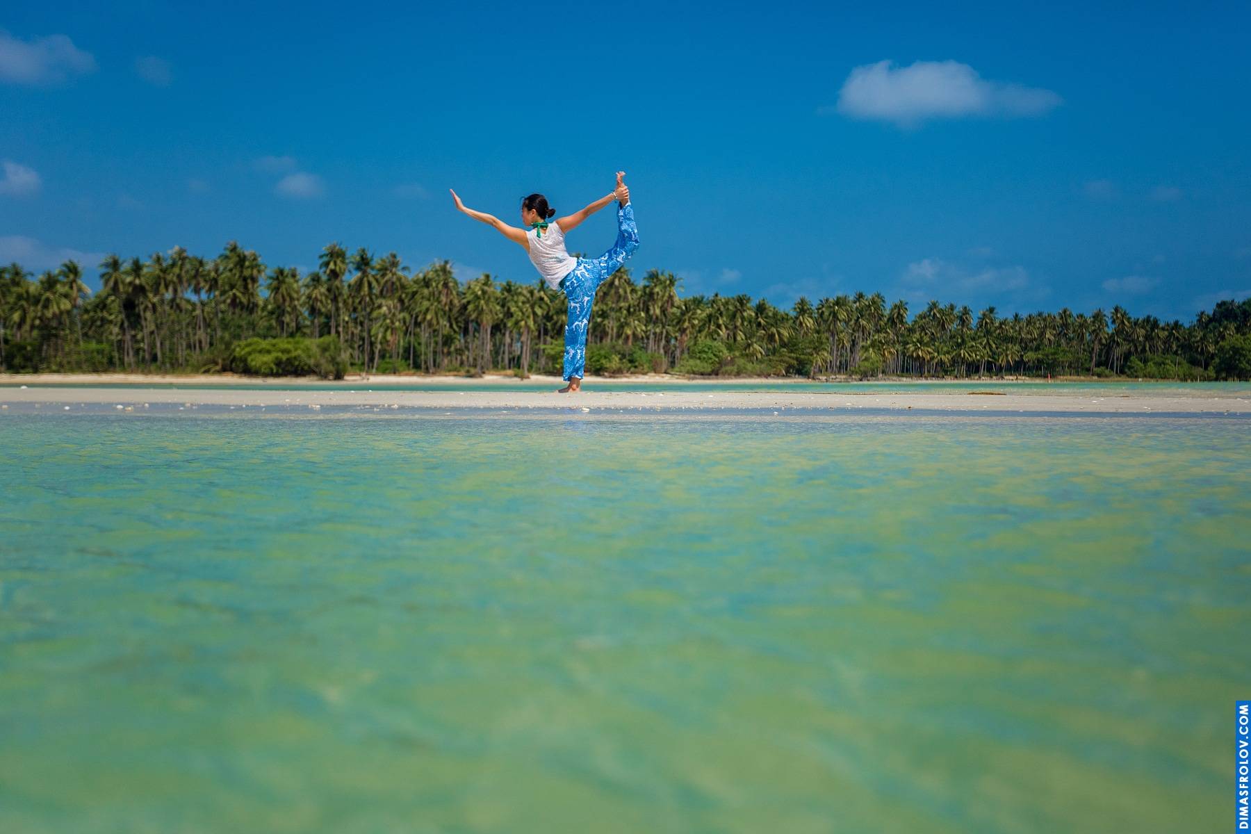 Joyful beach yoga: woman leaping with outstretched arms on a tropical shore